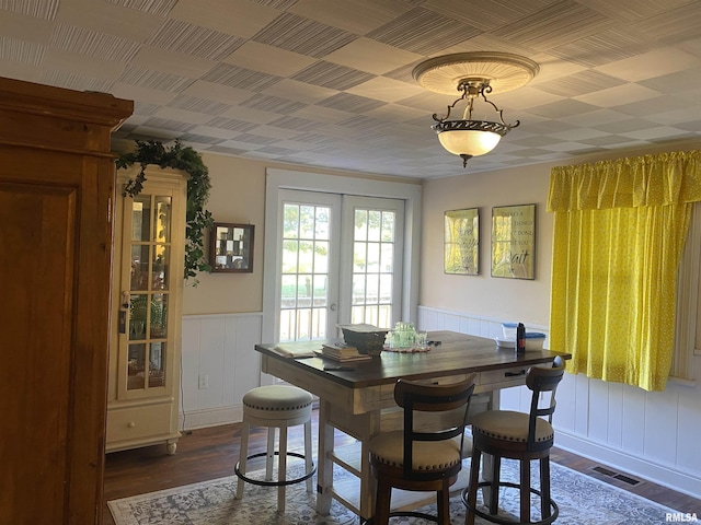 dining area featuring a wainscoted wall, dark wood-style floors, visible vents, and french doors