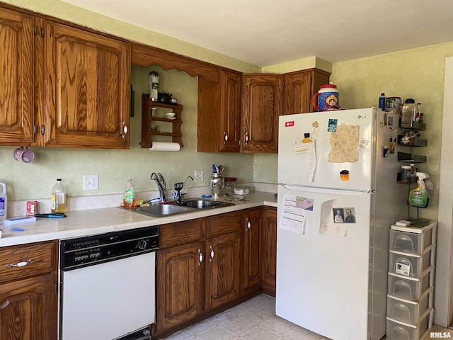 kitchen featuring light countertops, brown cabinets, a sink, and white appliances