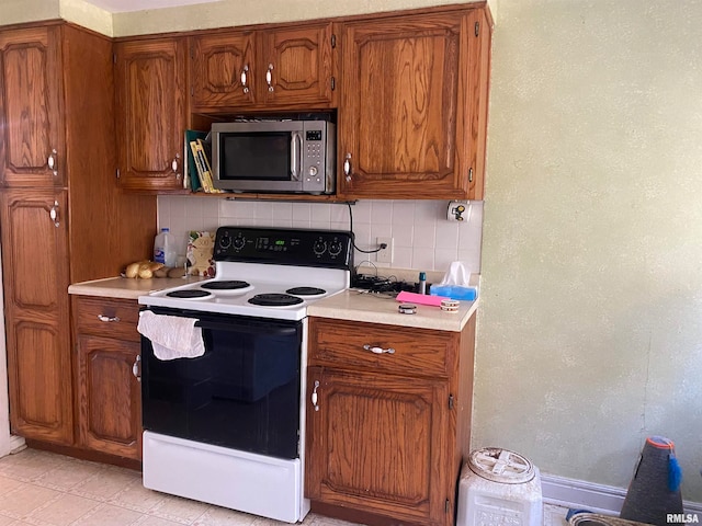 kitchen with light tile patterned floors, white electric stove, and backsplash