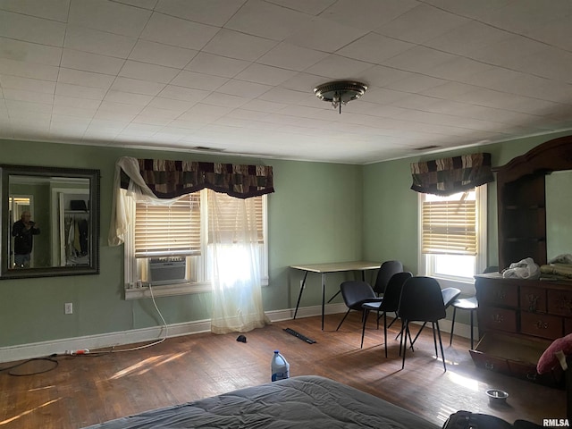 bedroom with cooling unit, wood finished floors, and baseboards