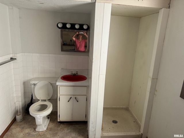 bathroom featuring vanity, a textured ceiling, tile walls, and toilet