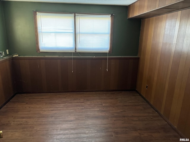 spare room with dark wood-type flooring and wooden walls