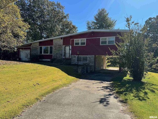split level home with a front lawn, a carport, stone siding, and aphalt driveway