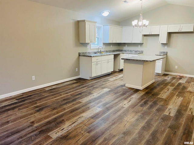 kitchen featuring white cabinets, light stone countertops, a kitchen island, and dark wood-type flooring