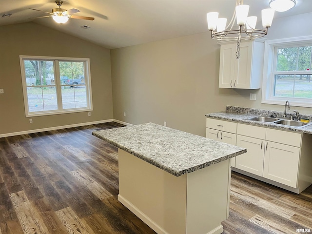 kitchen with dark wood-style flooring, visible vents, a kitchen island, a sink, and vaulted ceiling