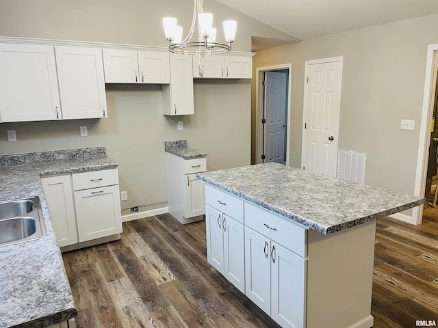 kitchen featuring a kitchen island, visible vents, white cabinets, dark wood finished floors, and decorative light fixtures