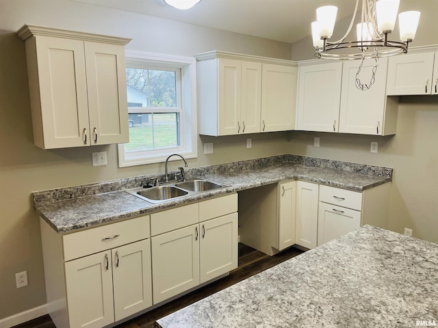 kitchen featuring a chandelier, dark wood-type flooring, a sink, white cabinets, and pendant lighting