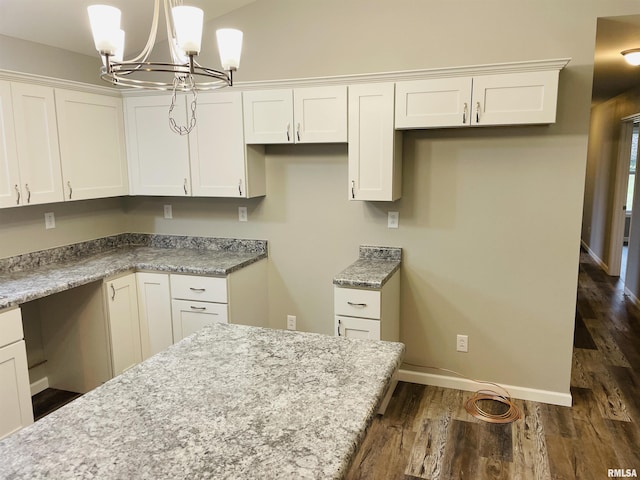 kitchen with dark wood-style flooring, built in study area, light stone countertops, and white cabinets