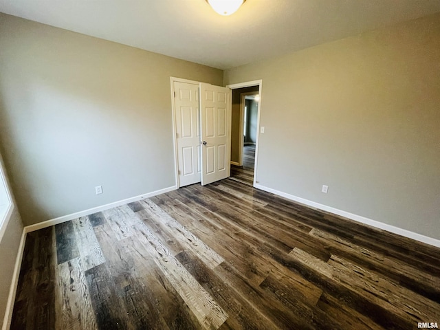 unfurnished bedroom featuring dark wood-type flooring and baseboards