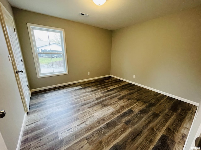 unfurnished room featuring baseboards, visible vents, and dark wood-type flooring