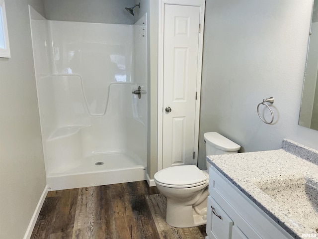 full bathroom featuring toilet, wood finished floors, vanity, baseboards, and a shower stall