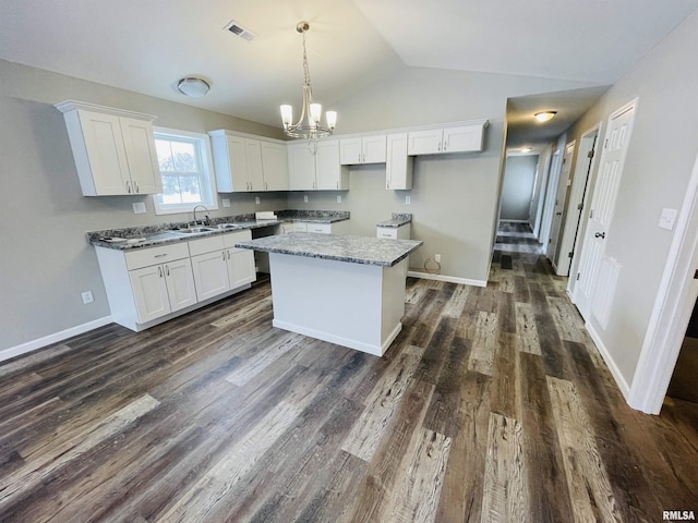 kitchen with light stone counters, dark hardwood / wood-style flooring, white cabinets, and a kitchen island