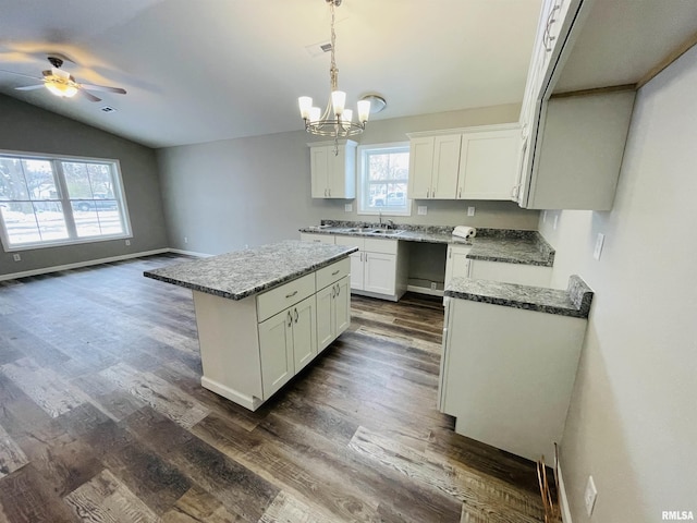 kitchen with lofted ceiling, white cabinetry, a center island, and dark hardwood / wood-style floors