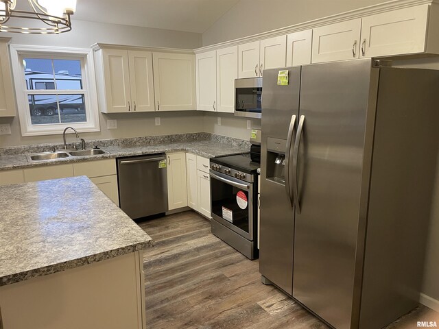 kitchen with stainless steel appliances, a sink, dark wood finished floors, and white cabinetry