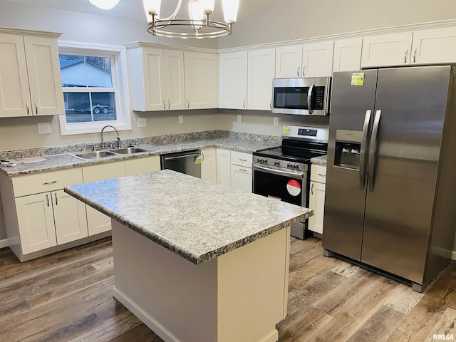 kitchen featuring light wood-type flooring, a kitchen island, appliances with stainless steel finishes, and a sink