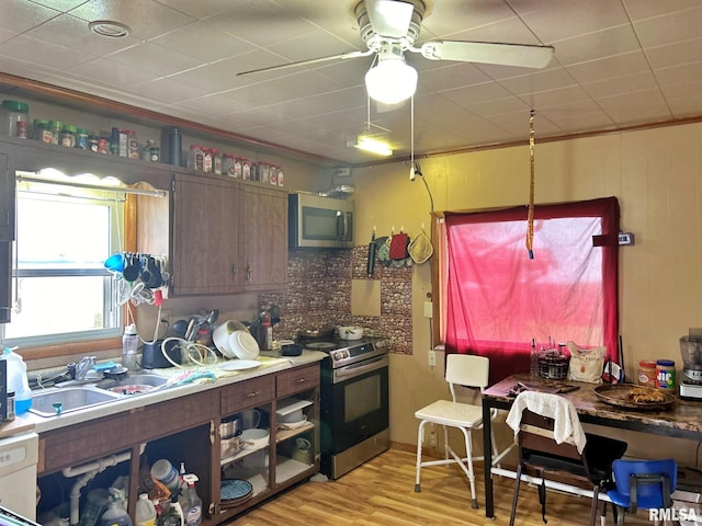 kitchen featuring stainless steel appliances, sink, ceiling fan, crown molding, and light wood-type flooring