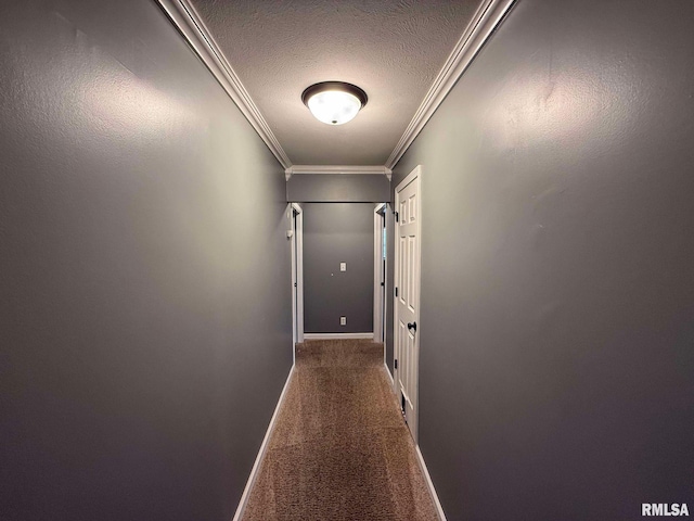 hallway with a textured ceiling, crown molding, and dark carpet