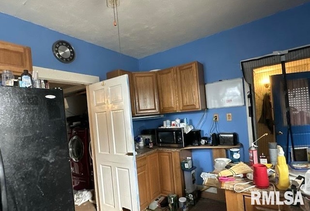 kitchen with black refrigerator and washer / clothes dryer