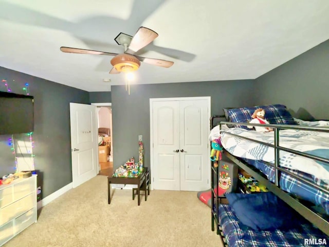 bedroom featuring ceiling fan, a closet, and light colored carpet