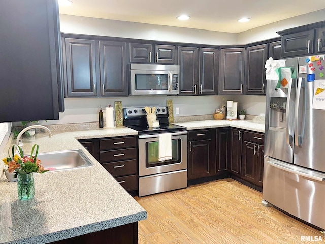 kitchen featuring dark brown cabinets, light hardwood / wood-style floors, sink, and appliances with stainless steel finishes