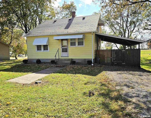 back of house with a yard, a carport, and roof with shingles