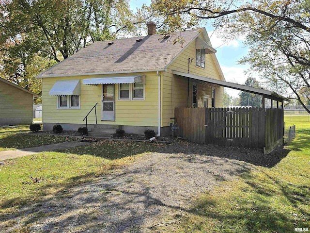 view of front of home with roof with shingles, a chimney, and a front yard