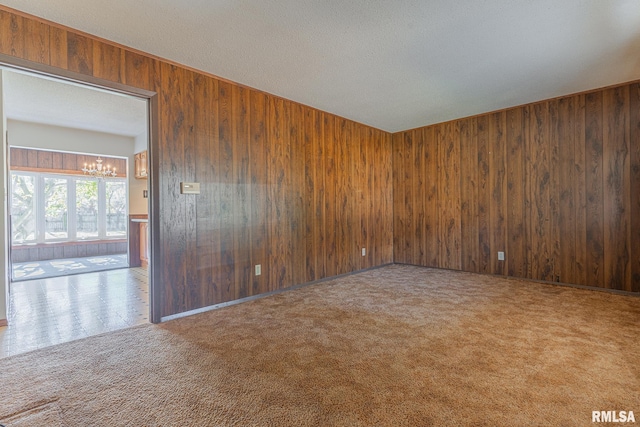 unfurnished room featuring wood walls and carpet