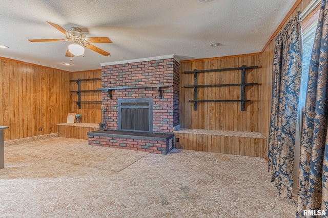 unfurnished living room featuring wooden walls, a textured ceiling, carpet flooring, and crown molding