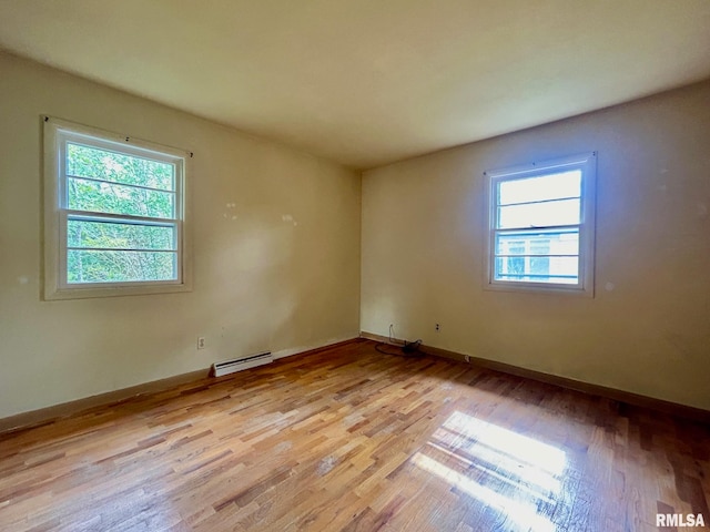 unfurnished room with a baseboard radiator and light wood-type flooring