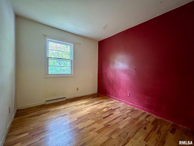 empty room with a baseboard heating unit and light hardwood / wood-style floors