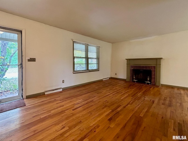 unfurnished living room featuring a brick fireplace, baseboard heating, and hardwood / wood-style floors