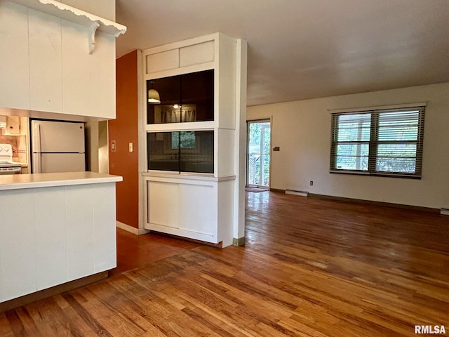 kitchen with dark hardwood / wood-style flooring, stainless steel range oven, white fridge, and white cabinets