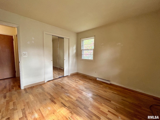 unfurnished bedroom with a baseboard heating unit and light hardwood / wood-style flooring