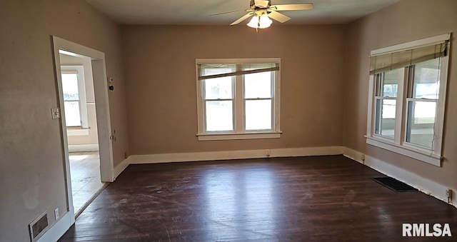 empty room featuring plenty of natural light, dark hardwood / wood-style floors, and ceiling fan