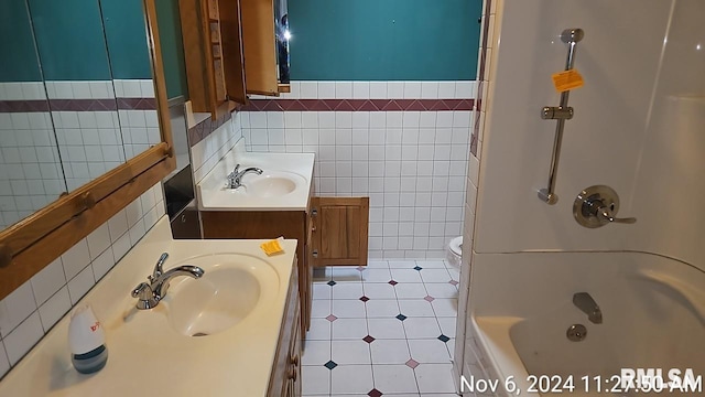 full bathroom with tile walls, vanity, shower / tub combination, and toilet