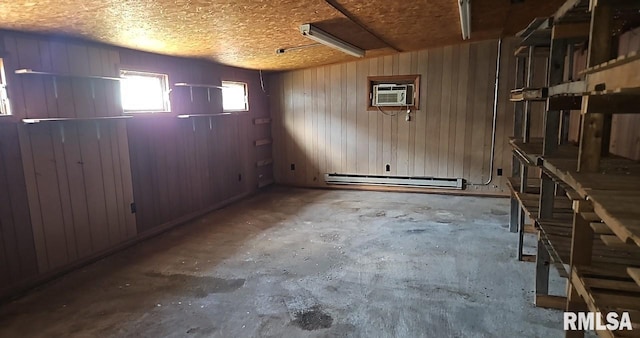 basement with a textured ceiling, a baseboard radiator, wooden walls, and an AC wall unit