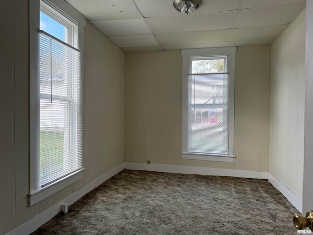 carpeted spare room featuring a drop ceiling and plenty of natural light