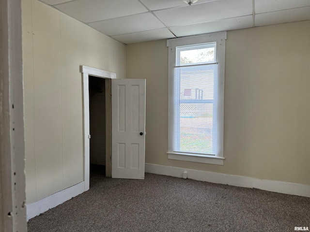 unfurnished room with a paneled ceiling and dark carpet