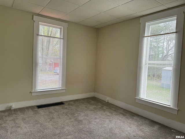 carpeted empty room with plenty of natural light and a paneled ceiling