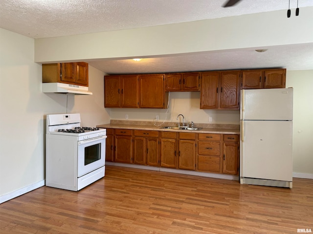 kitchen featuring sink, white appliances, a textured ceiling, and light hardwood / wood-style floors