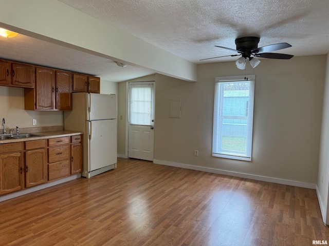 kitchen featuring light wood-type flooring, a wealth of natural light, a textured ceiling, and white fridge