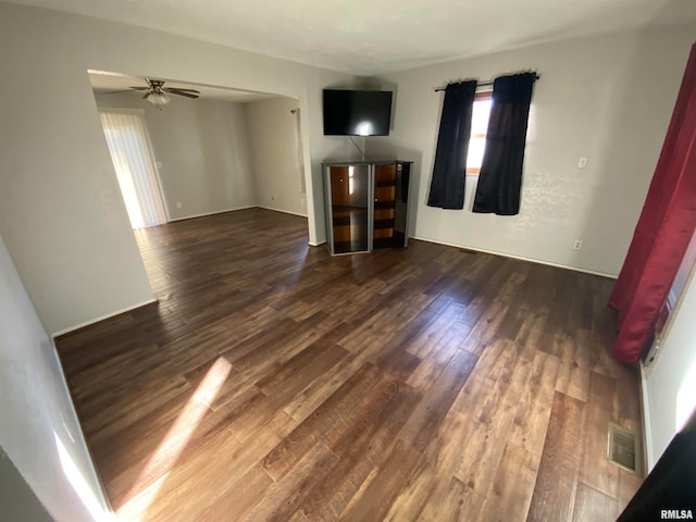 unfurnished living room featuring dark wood-type flooring and ceiling fan