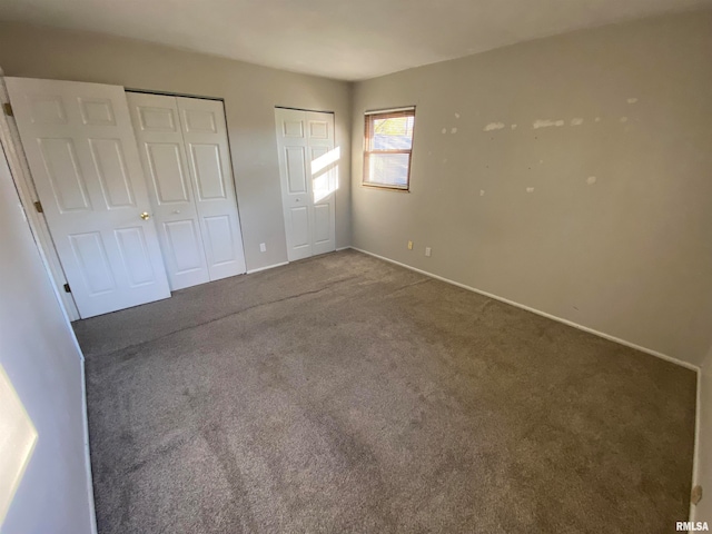 unfurnished bedroom featuring carpet flooring and two closets