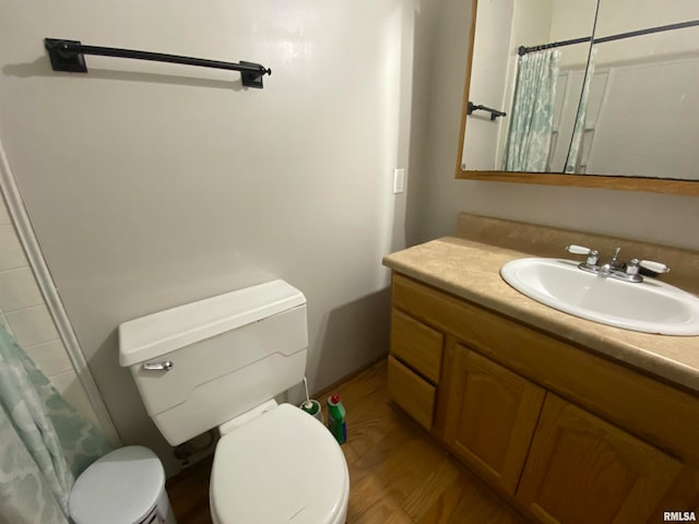 bathroom with hardwood / wood-style flooring, vanity, toilet, and curtained shower