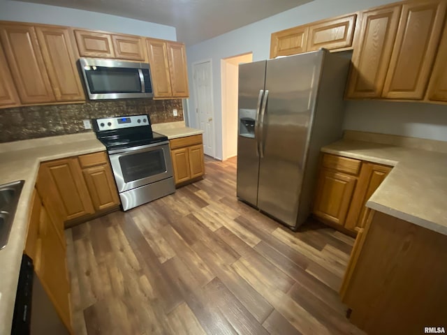 kitchen featuring tasteful backsplash, appliances with stainless steel finishes, and wood-type flooring