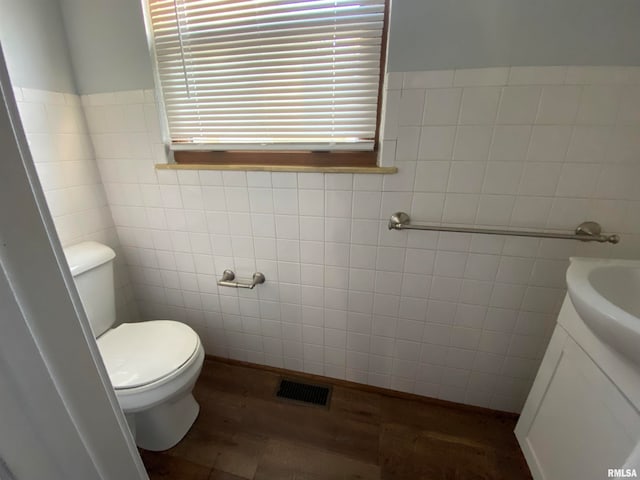 bathroom with tile walls, hardwood / wood-style floors, vanity, and toilet