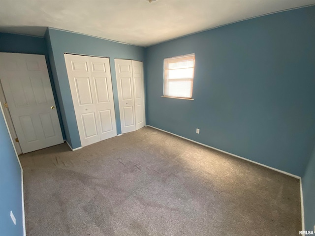 unfurnished bedroom with carpet floors and two closets