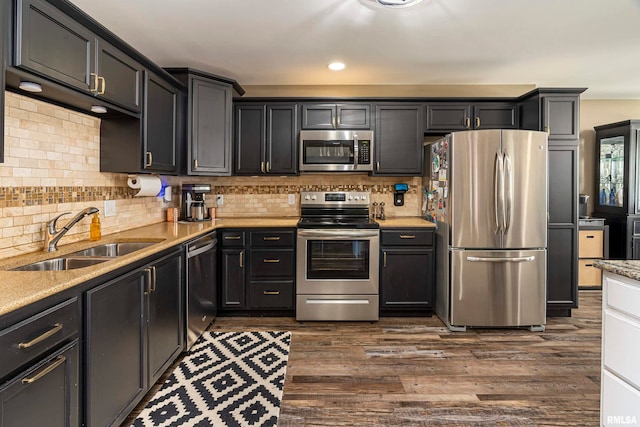 kitchen with backsplash, sink, light stone countertops, dark hardwood / wood-style flooring, and stainless steel appliances