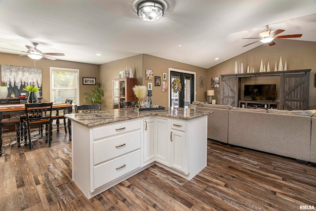 kitchen featuring lofted ceiling, white cabinetry, dark wood-type flooring, and dark stone counters