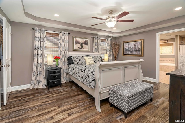 bedroom featuring dark hardwood / wood-style floors, ceiling fan, multiple windows, and ensuite bath